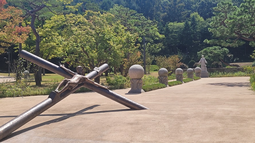 남양 성모 성지 묵주기도의 길과 예수님이 누워있는 모습의 십자가, 그리고 묵주알을 형상화 한 화강암 조형물