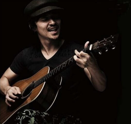 강산에-거꾸로-강을-거슬러-오르는-저-힘찬-연어들처럼-강산에가-모자를-쓰고-검정-반팔티를-입고-기타를-치며-노래-부르는-사진