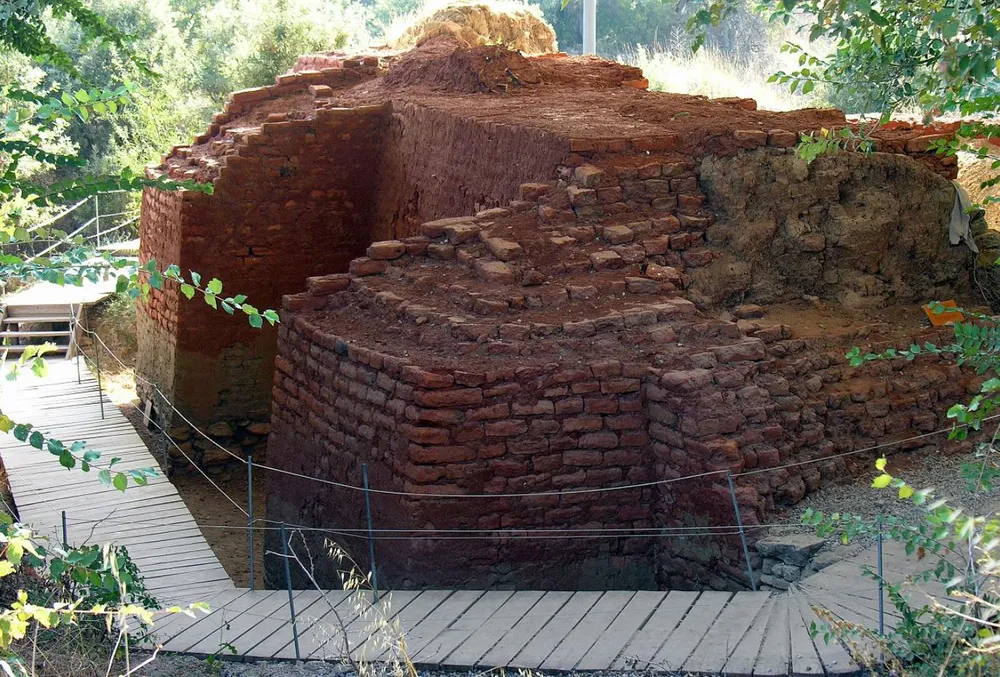붉은 흙과 벽돌로 구성된 고대 성벽 유적. 주변에 나무 데크 길이 설치되어 있고, 벽면은 복원 및 보존 작업의 흔적이 보인다. 트로이 유적 중 가장 오래된 시기의 구조물로 여겨진다.