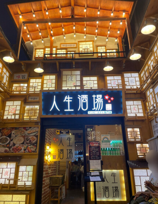 인생술집 입구 현관 사진 현관에 '인생술집'이라고 한문으로 적힌 간판이 있다. 한옥 느낌의 인테리어에 전반적으로 조명등이 화려하게 장식되어 있다.