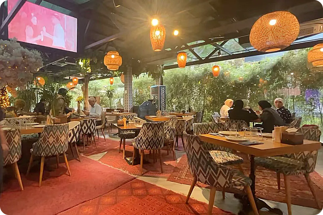 샤슬릭-내부-알록달록한-의자와-따뜻한-오랜지색-전등-창문밖-숲