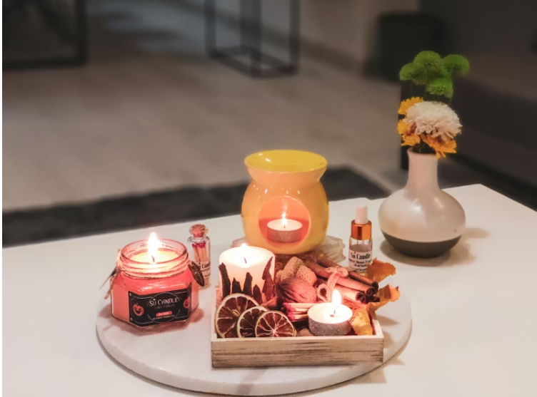 따뜻한 조명 아래 향초와 아로마 오일이 놓인 테이블, 아늑하고 정돈된 실내 공간.