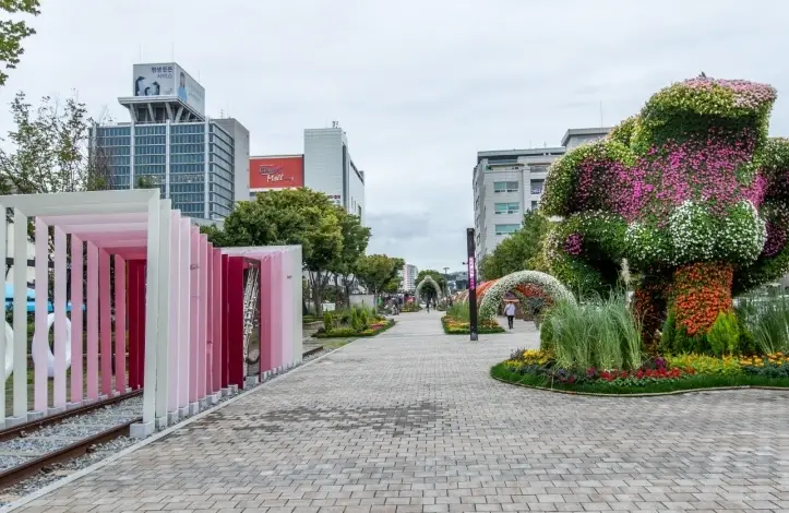 낮의 월화거리 우측 나무조형물 좌측 흰 사각형 조형물이 줄지어 서있음