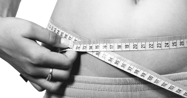 줄자로 허리 둘레를 측정하고 있는 여성