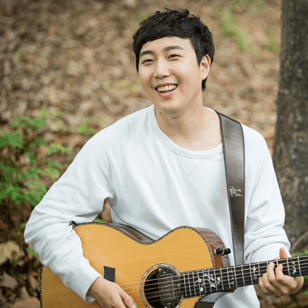 장범준이-하얀색-맨투맨-티를-입고-기타를-어깨에-맨-채-환하게-웃고-있는-사진