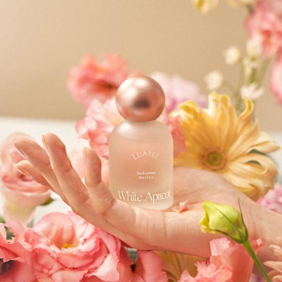 꽃을 배경으로 향수병을 들고있는 사람의 손부분