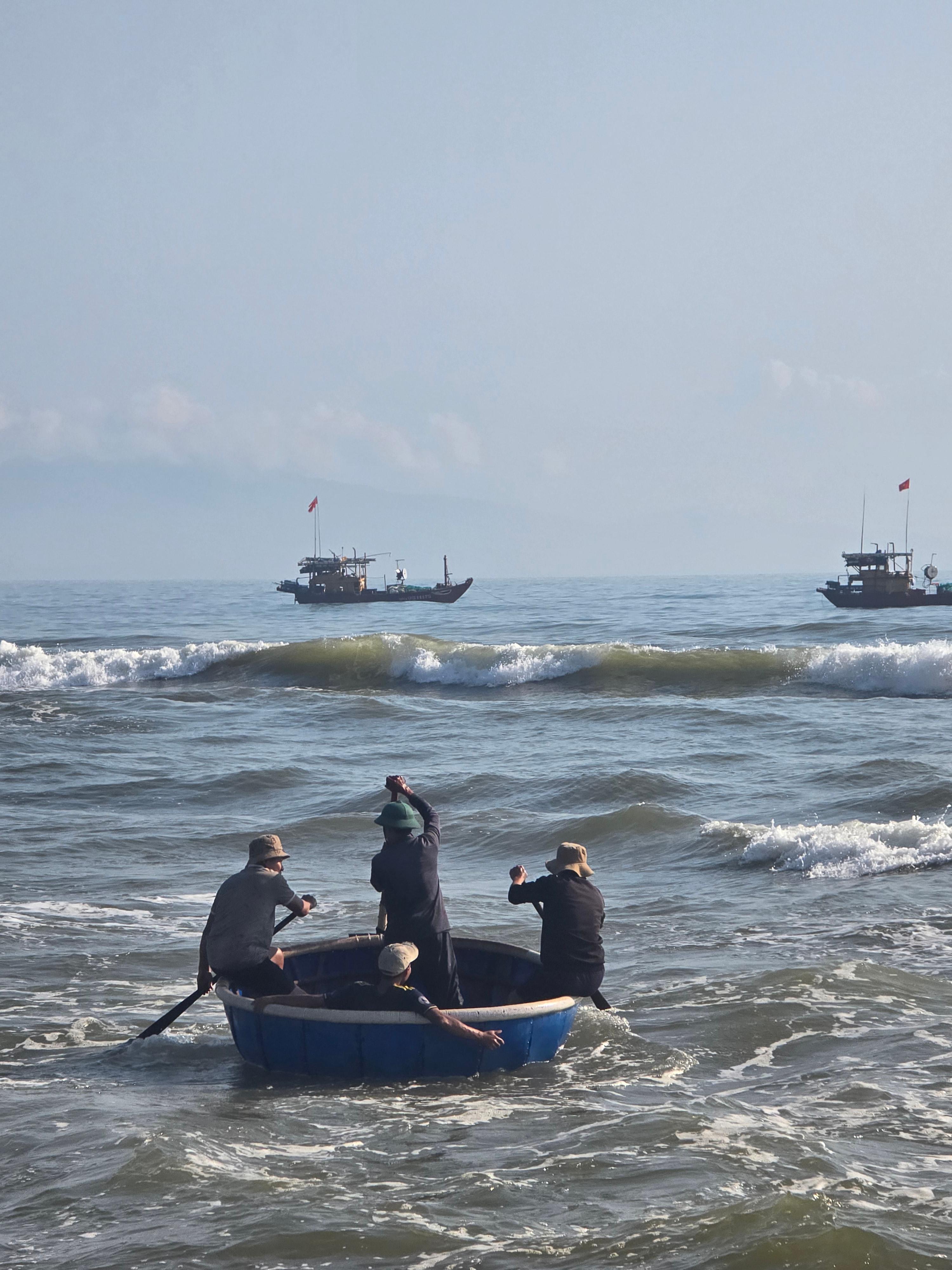 베트남 어부들이 통배를 타고 파도를 넘어 바다로 출항하는 모습