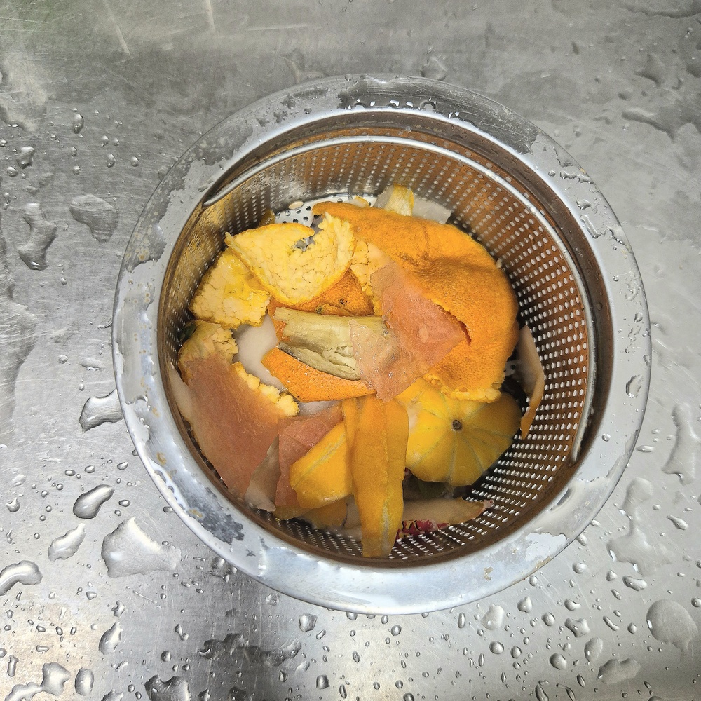 싱크대 거름망에 과일껍질을 두고 물기를 줄이는 모습