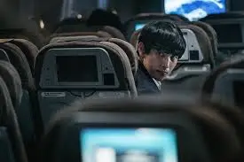 비상선언 주인공이 비행기안에서 뒤를 돌아보고 있는 장면