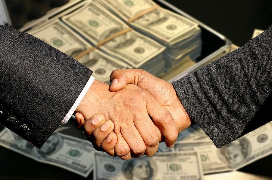 돈을 배경으로 두 사람이 악수하는 모습