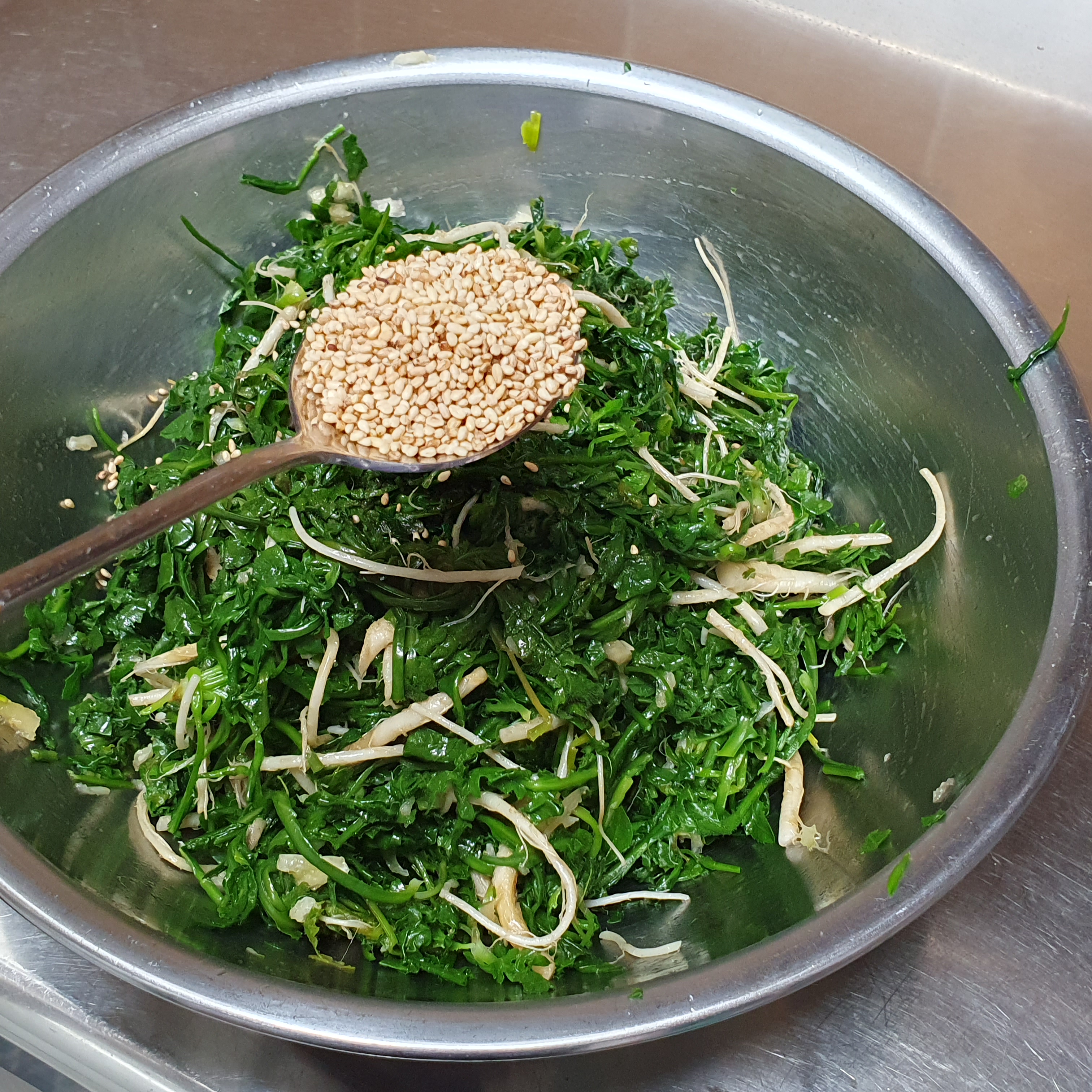 완성된 냉이 무침에 통깨를 뿌리는 사진