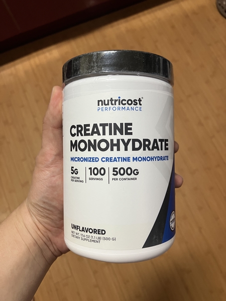 Nutricost 크레아틴 모노하이드레이트 500g 통을 손에 들고 있는 모습, 5g 1회 제공량과 100회 분량 표시
