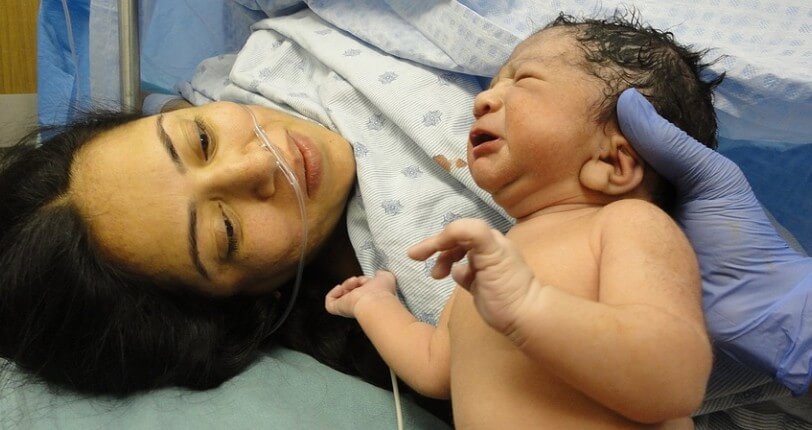 산모가 출산한 아이를 지긋이 바라보는 사진입니다.