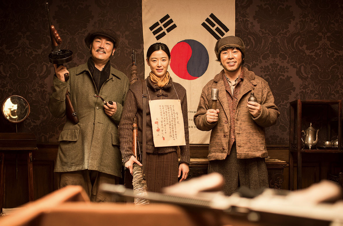 태극기 앞에서 속사포, 안옥윤, 황덕삼 세 사람이 각자 무기를 들고 나란히 서 있는 장면
