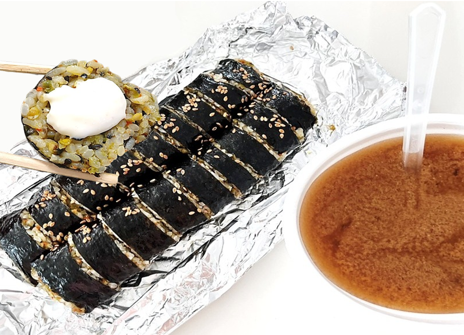 호일 위에 진주 땡초김밥 두 줄이 있고, 땡초김밥 하나를 마요 수제 소스에 찍은 모습, 그 옆에는 시락국 한 그릇이 놓여 있다.