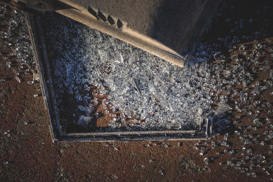 From above of pile of broken glass and metal frame scattered on rough ground on sunny day