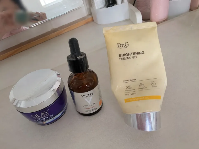 피부과 레이저 시술 후 주의해야 할 성분인 레티놀 크림, 비타민C 미백 앰플, 필링젤 각질제거제가 화장대 위에 놓여 있는 모습