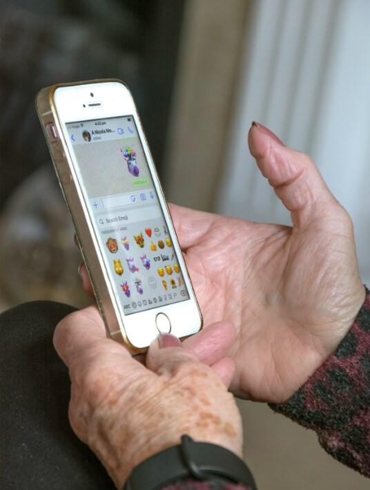 이모티콘 메시지를 전송 중인 고령자의 손과 스마트폰 화면