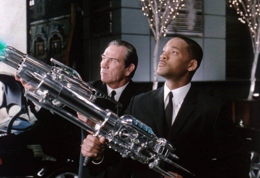 요원 K와 J 가 소총을 들고 쳐다 보는 장면