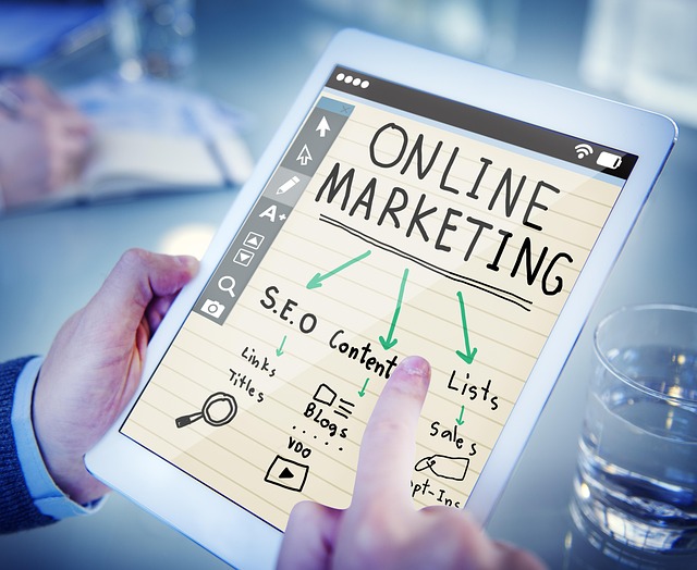 태블릿에 online marketing 이라는 영어가 적혀있고 해당 내용에 대한 그림과 글이 적혀있고 , 손가락이 그것을 가리키는 모습