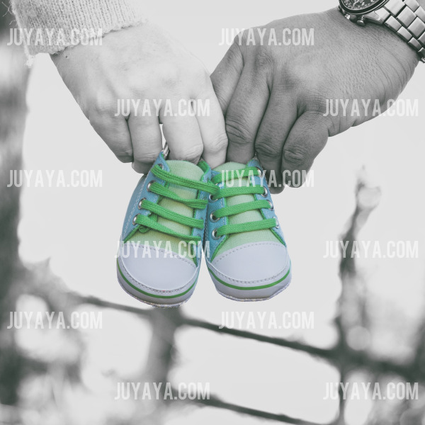 초록색 운동화를 들고 있는 부모의 손. 새로운 가족을 맞이하는 기대감과 설렘을 담은 이미지.