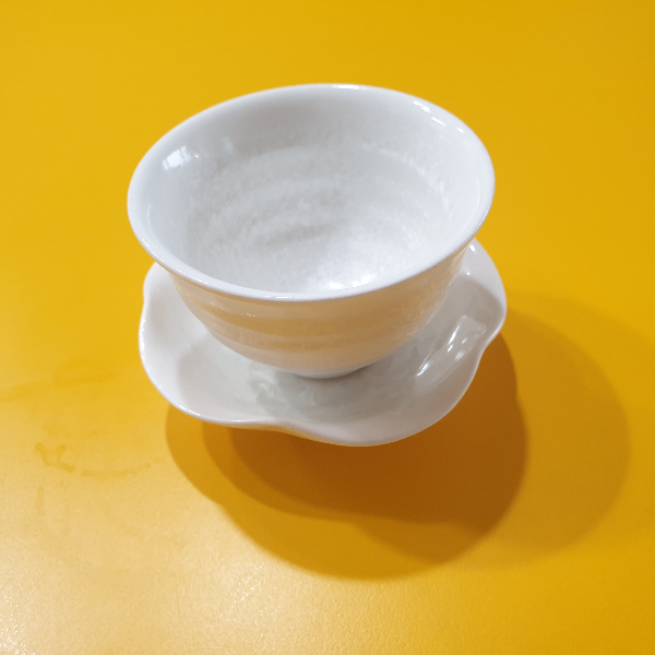 노란 테이블 위에 찻잔이 놓여있다. 찻잔 받침은 꽃님과 비슷하게 생겼다.