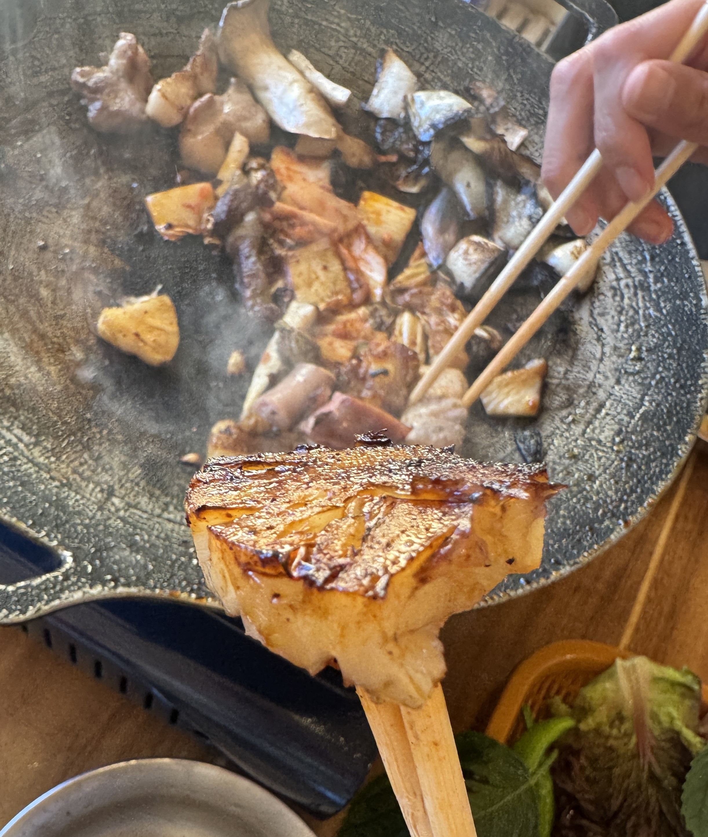 숯불 바베큐 불판 위에서 노릇하게 구워진 파인애플을 젓가락으로 집은 모습&amp;#44; 고기와 함께 즐기는 캠핑 바베큐 디저트