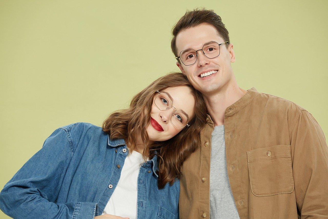 안경을 낀 남녀가 밝게 웃고 있는 사진