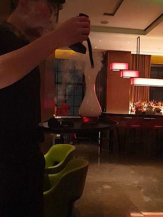 훈연 기계로 칵테일을 훈연 중인 직원