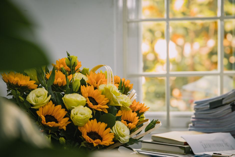 A vibrant sunflower and rose bouquet placed by a sunlit window, creating a warm and inviting atmosphere.
