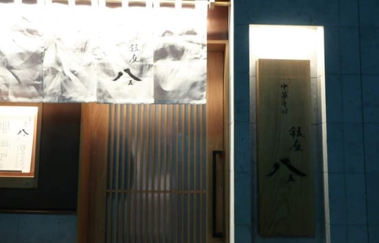 파란색 외벽과 흰색 노렌(일본식 천)이 위에 매달려 있는 가게 입구