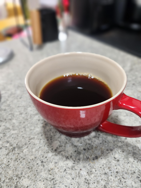 붉은 커피 잔에 커피가 담겨 있는 모습