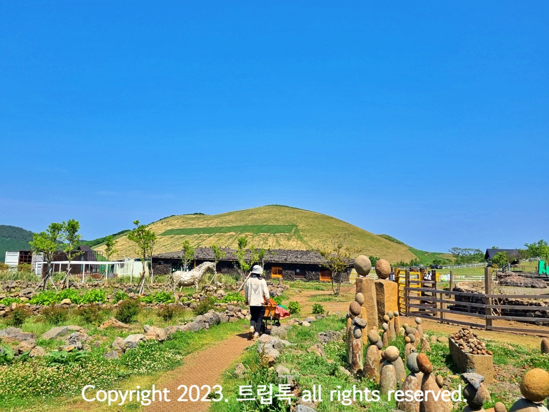 새별오름을 배경으로 사육사가 외발수레를 끌고 간다.