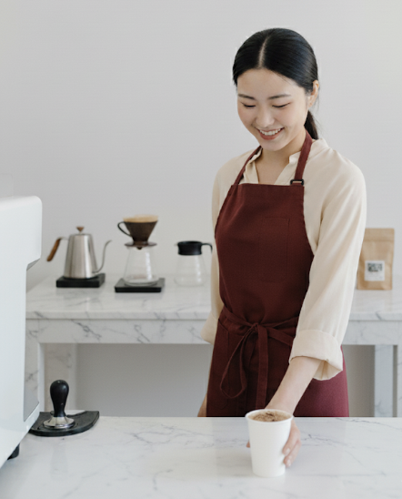 여자 바리스타가 픽업대 위에 테이크 아웃 커피를 올려놓고 있다.