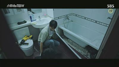 화장실 욕조를 뜯어내고 검은 비닐봉지를 발견하는 사진입니다.