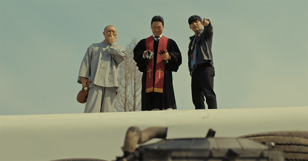 목스박 영화의 한장면 목사, 스님, 박수무당이 나란히 서서 아래를 내려다 보고 있다.