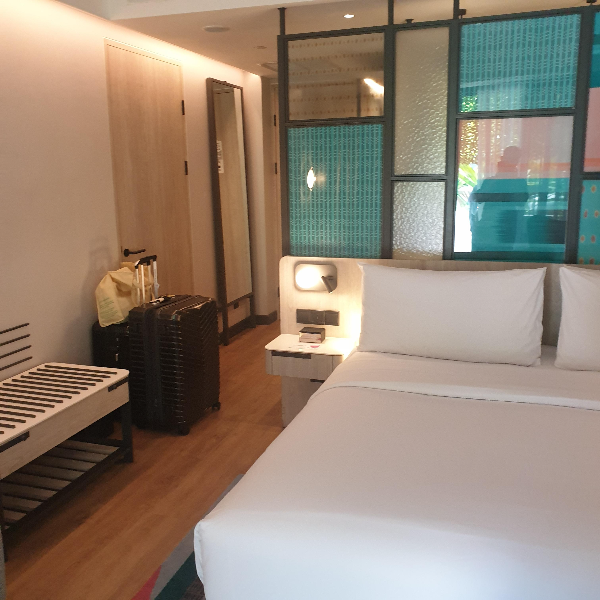 초록색과 불투명 투명 유리로 된 파티션 앞에는 침대, 뒤에 욕실이 있다. 케리어도 보인다.