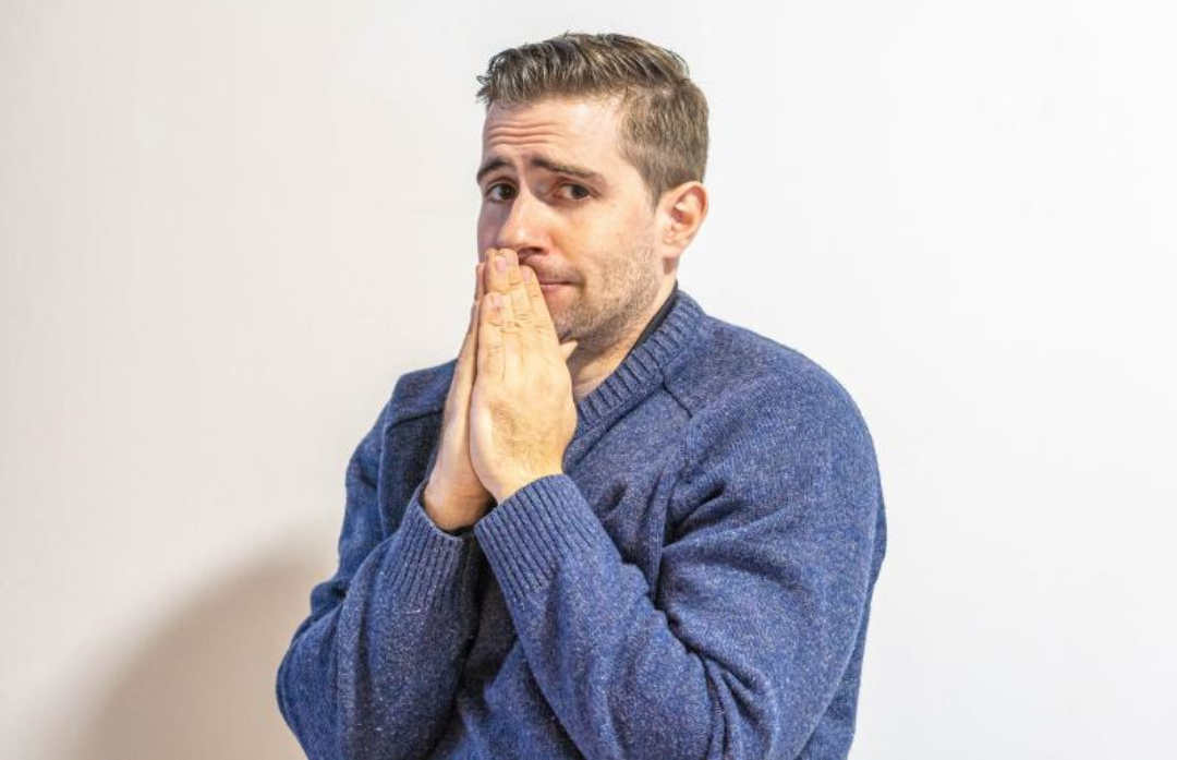 한 외국 남성이 불안한 표정을 지으며 손을 모으고 있다.