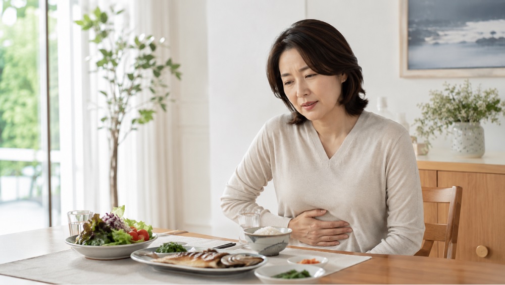 식사 후 소화 불편감을 느끼며 배를 짚고 있는 중년 여성과 건강한 식탁