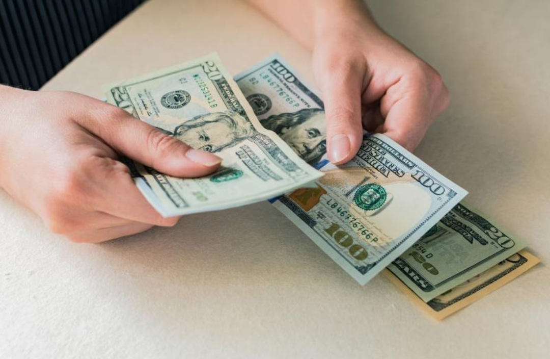 한사람이 달러 지폐를 세고 있다.