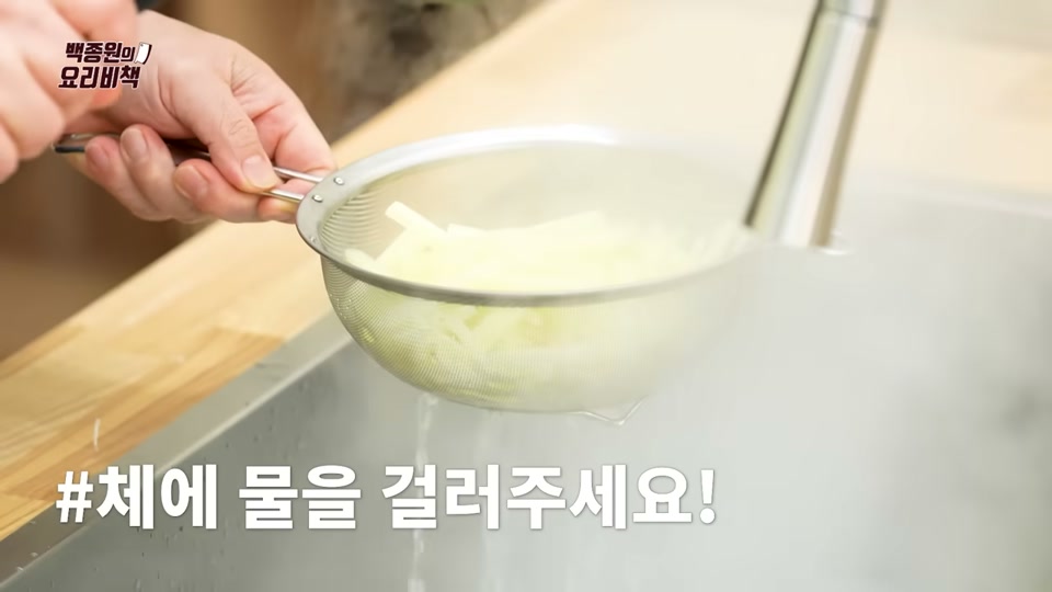 데친 감자를 체에 밭쳐 물기를 빼는 장면