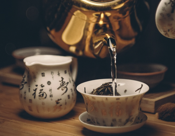 테이블 위에 찻잔과 공도배가 올려져 있다. 포트로 찻잎이 있는 찻잔에 물을 붓고 있다.