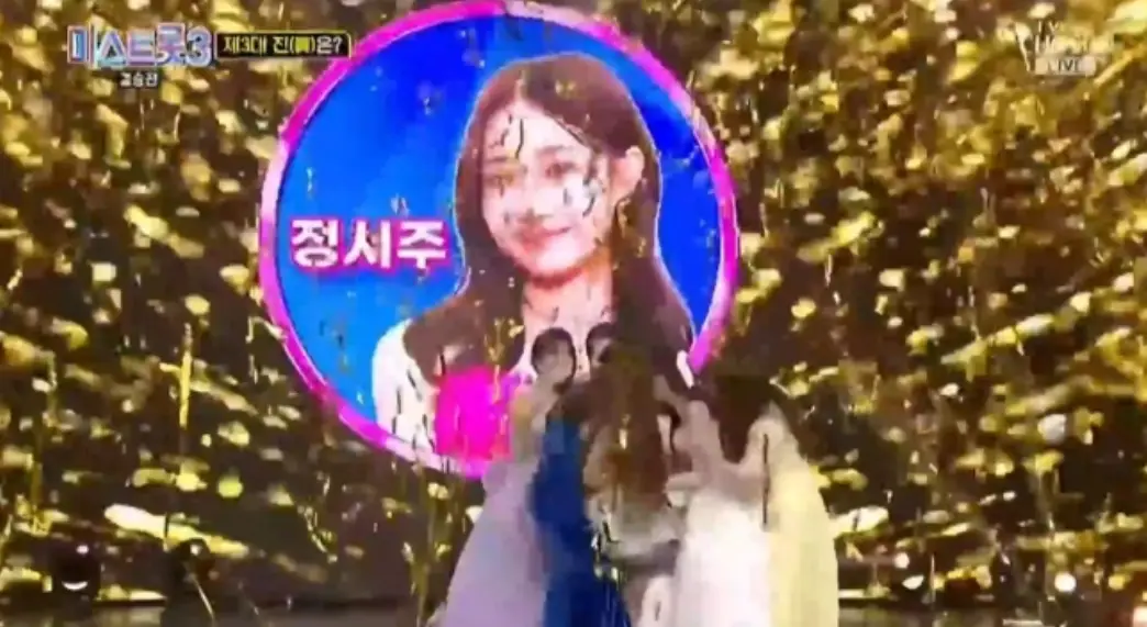 미스트롯3- 검은색 금빛 꽃이 내리는 배경 정서준 얼굴이 크게 나온 이미지 앞 출연자들이 정서주를 안아주는 모습