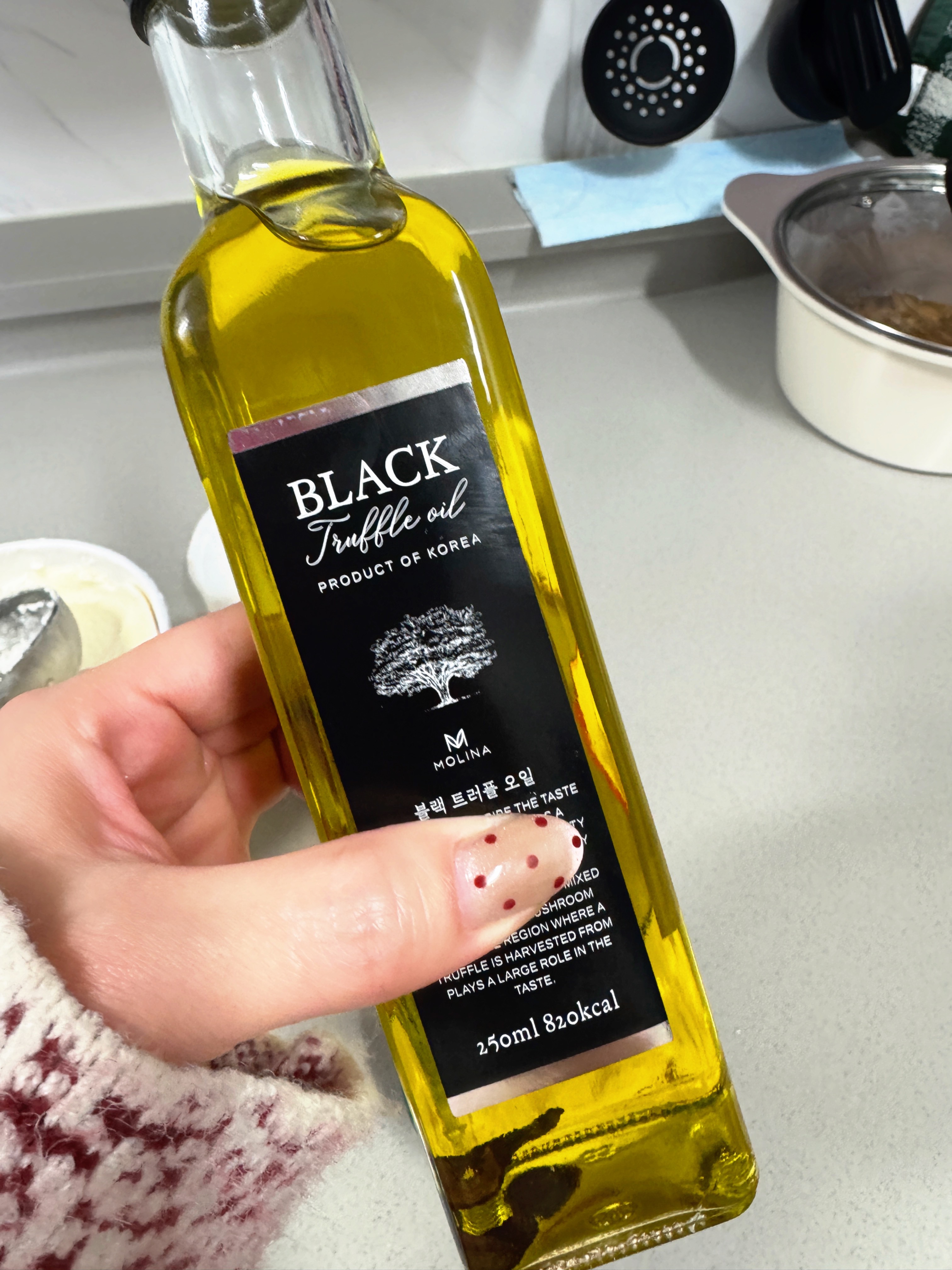 몰리나 블랙 트러플 오일 250ml 입문용 트러플 오일 실사용 사진, 손에 들고 주방에서 앞면 라벨이 보이게 촬영한 모습
