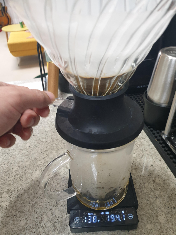 스위치를 누르고 있는 모습. 드리퍼에서 추출액이 아래로 떨어지고 있다.