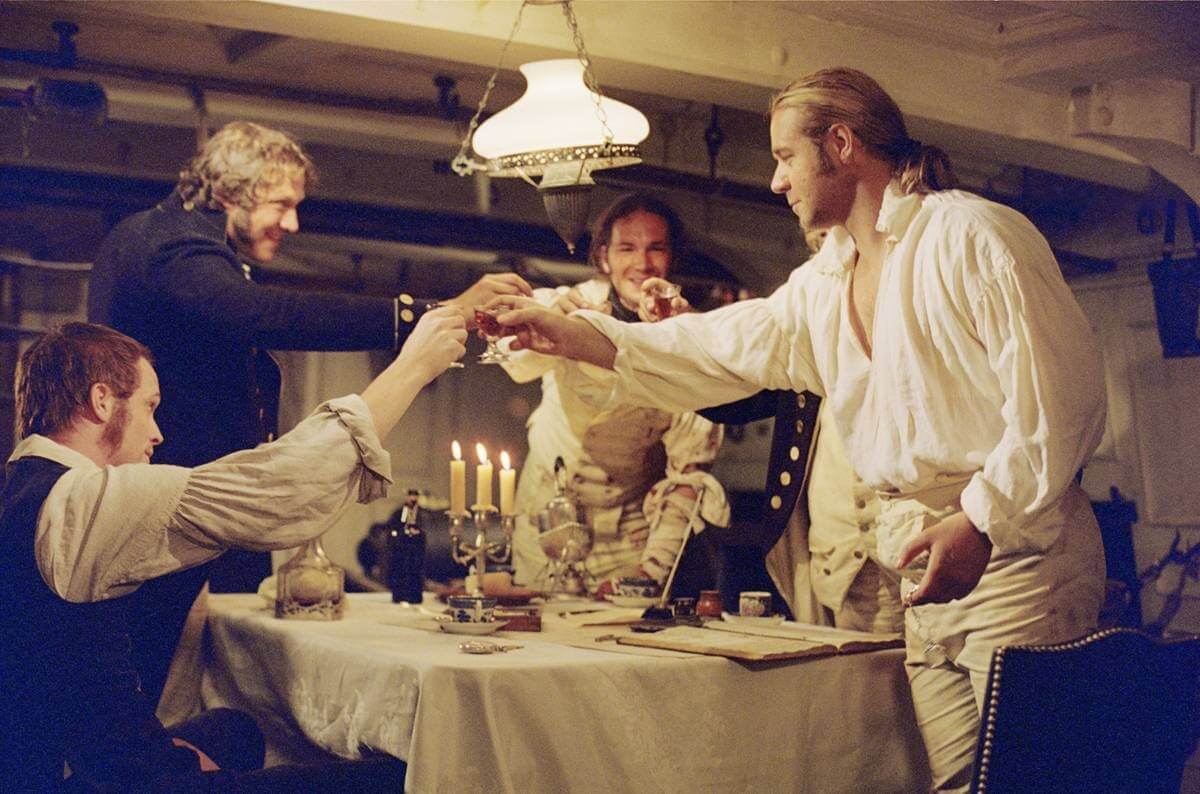 마스터 앤드 커맨더: 위대한 정복자 영화 속 잭 오브리와 스티븐 매튜린을 비롯한 인물들이 건배를 하고 있는 모습
