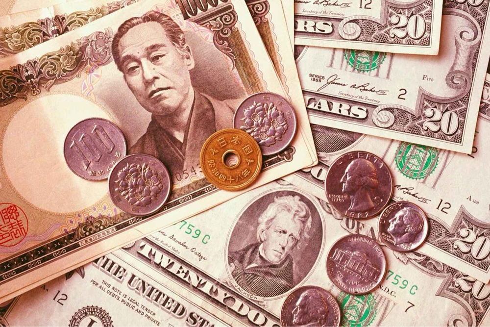 Japanese Yen and US Dollar banknotes scattered, representing currency volatility after Japan's GDP announcement.