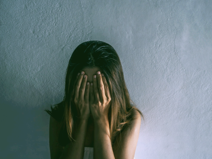 공황장애 증상 자가진단 치료 극복법에 관한 글의 이해를 돕기위한 이미지 : 여성이 얼굴을 감싸고 고개를 숙이고 있다