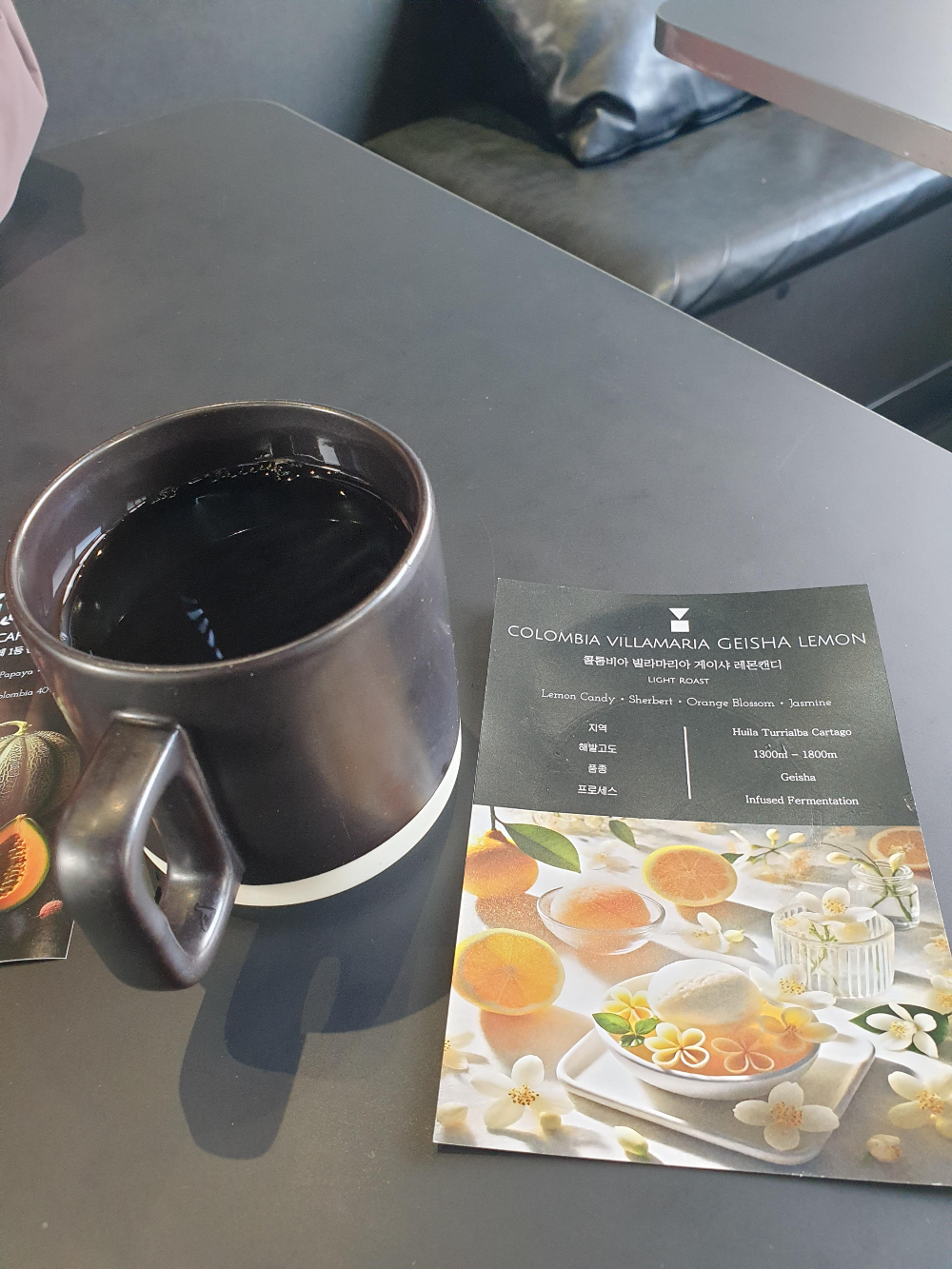 레몬 그림이 있는 컵노트와 핫 커피가 테이블 위에 있다.