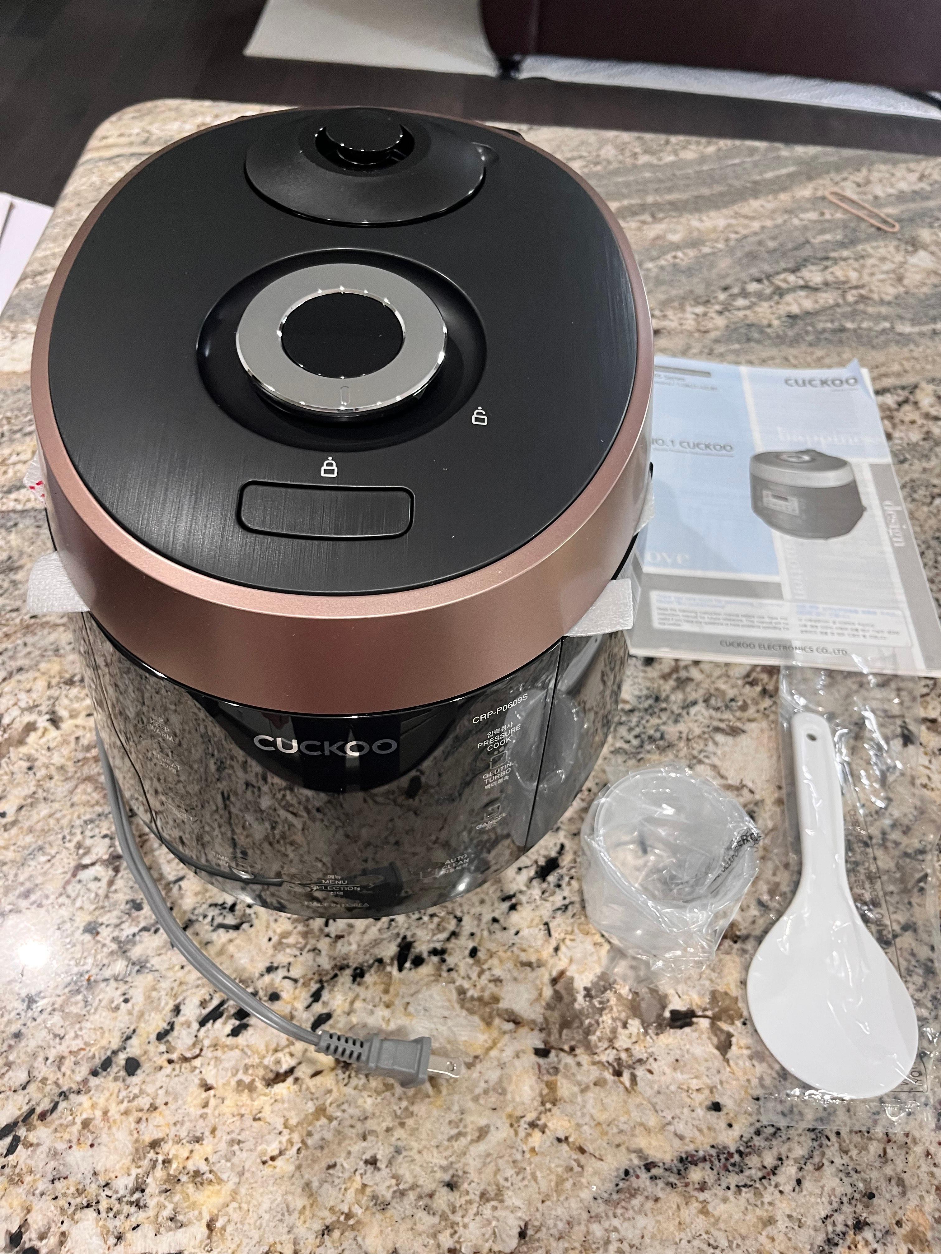 쿠쿠 압력 밥솥과 설명서, 밥주걱, 계량컵이 함께 있는 이미지